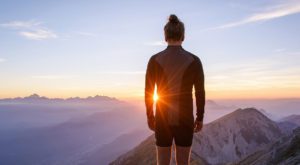 A person standing on top of a mountain at sunset.