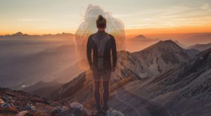 A person standing on top of a mountain at sunset.