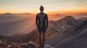 A person standing on top of a mountain at sunset.