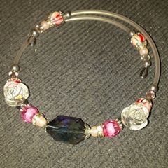 A bracelet with beads and wire is sitting on the floor.
