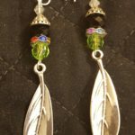 A pair of earrings with green beads and silver feathers.