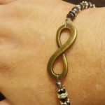 A person wearing a bracelet with an infinity symbol on it.