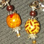 A pair of earrings with brown beads and yellow designs.