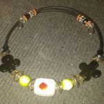 A necklace with beads and an orange square.