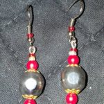 A pair of earrings with red and silver beads.