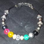 A bracelet with different colored beads and silver chains.