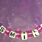 A purple background with the word smile spelled out in beads.