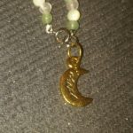 A necklace with a gold moon charm on it.