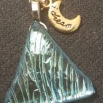 A blue glass pendant with a moon charm.