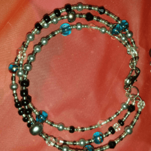 A necklace with beads and silver chain on pink cloth.