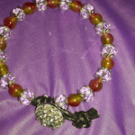 A purple and yellow beaded bracelet with a flower charm.