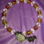 A necklace of beads and a flower on purple cloth.