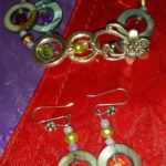 A pair of earrings and a bracelet on a red cloth.