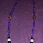 A purple necklace with gold and black beads.