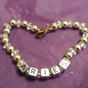 A heart shaped bracelet with the word aries spelled out in beads.