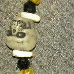 A skull bead with yellow beads on the side.