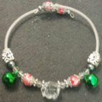 A bracelet with green and red beads on it.