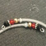 A pair of silver earrings with red and black beads.