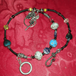 A necklace with beads and a key chain on it.