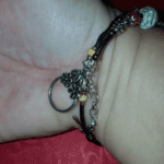 A person 's hand wearing a bracelet with a ring on it.