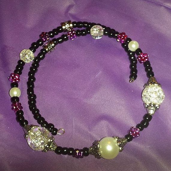 A purple and black necklace with pearls on it.