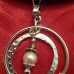 A silver key chain with a pearl hanging from it.