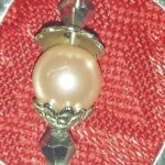 A close up of a pink pearl on top of a red cloth.