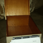 A wooden box with a lid open and several papers inside.