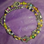 A bracelet with different colored beads and silver hamsa.