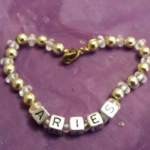 A heart shaped bracelet with the word aries on it.